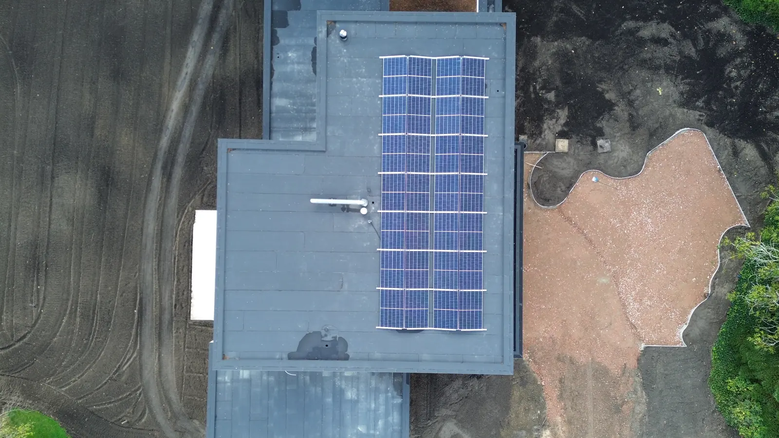Dronebeeld recht boven een plat dak met oost-west opgestelde zonnepanelen